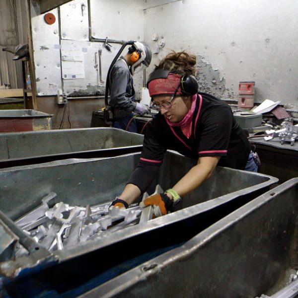 SAF Team member picking up aluminum casting products from a bin.